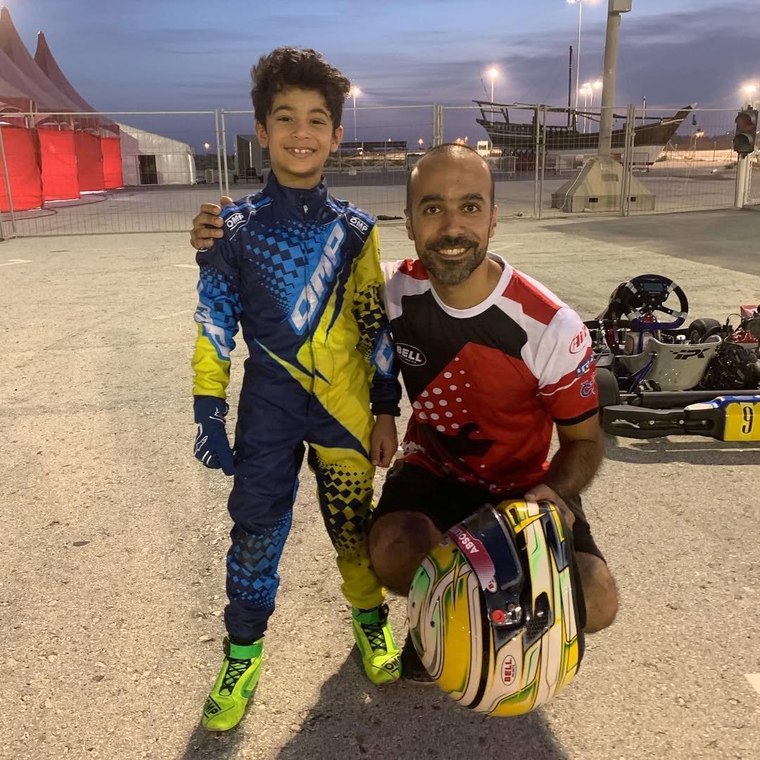 A young Khalid Al-Najjar with his coach beside the kart at dusk, Bahrain International Karting Circuit