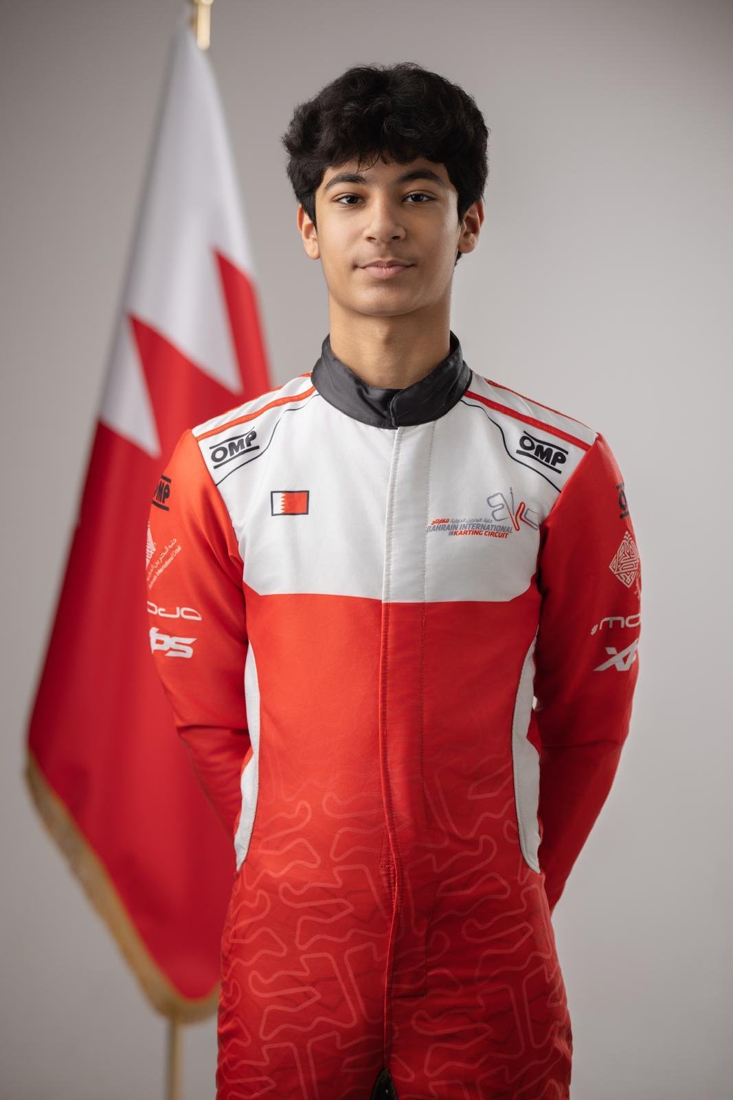 Khalid Al-Najjar in his red and white Team Bahrain race suit, the Bahraini flag behind him